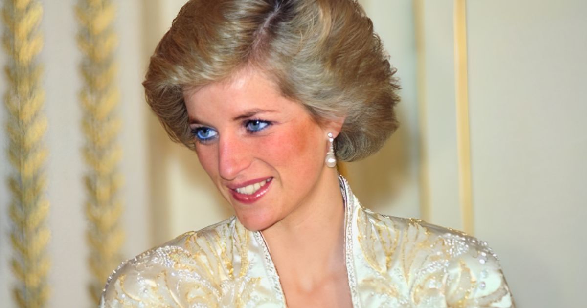 Princess Diana wearing white suit and pearl earrings, smiling warmly at a royal event.