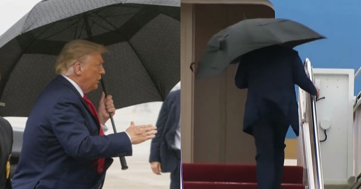 President Donald Trump struggles to close his umbrella while boarding Air Force One as an aide rushes to assist in the rain